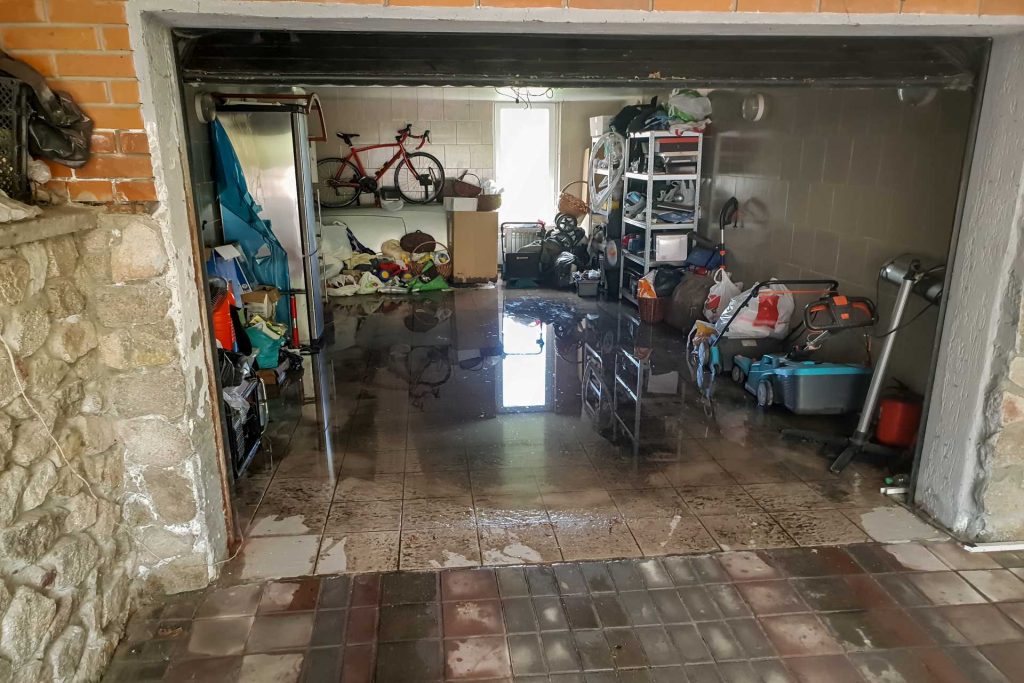 Photo of flooded garage with everything moved out of the water | Featured image for Water Damage Repairs blog by BetaBoard.