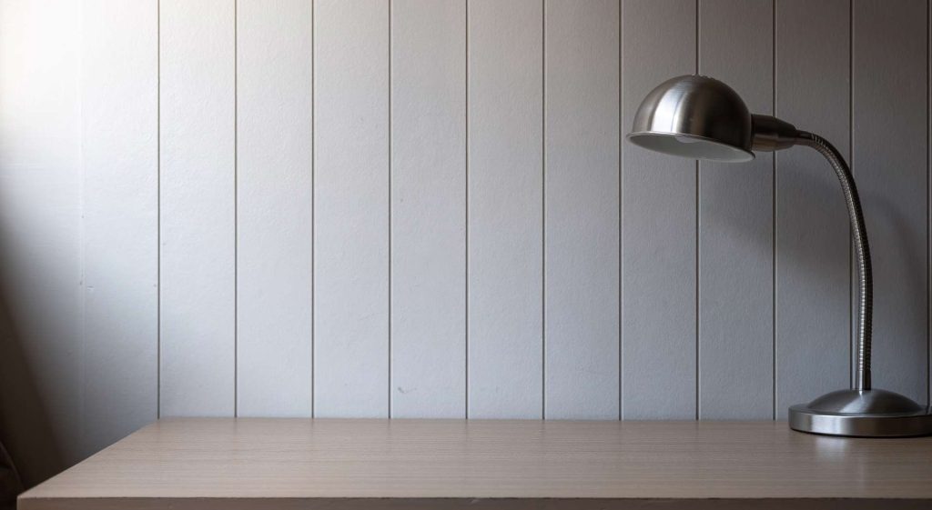 Workdesk with a lamp in front of a cement sheet wall | Featured image for What is Fibre Cement Sheeting Used For blog from BetaBoard.