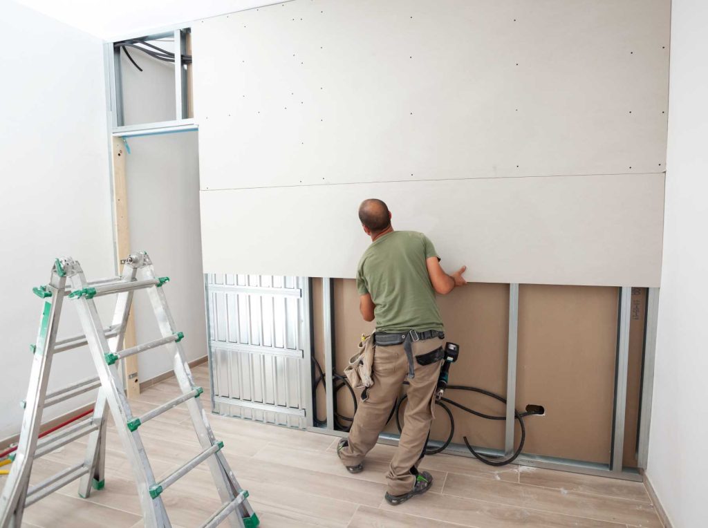 Man hanging plasterboard | Featured image for the How to Properly Hang Plasterboard blog from BetaBoard.