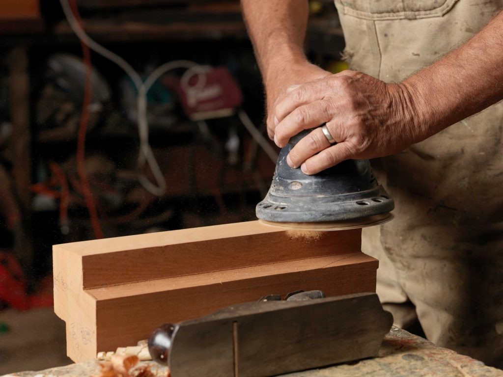 Man using a disc sander on a piece of timber | Featured image for the Sanding Guide for Beginners blog from BetaBoard.