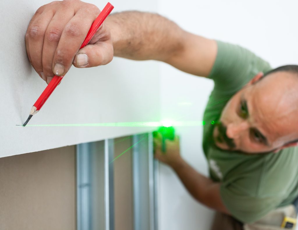 Worker building a plasterboard wall | Featured image for the How to Properly Hang Plasterboard blog from BetaBoard.