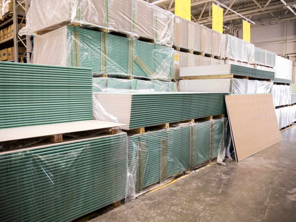 Sheets of platerboard stacked in a warehouse | Featured image for the Choosing the Right Plasterboard Thickness: A How to Guide blog from BetaBoard.