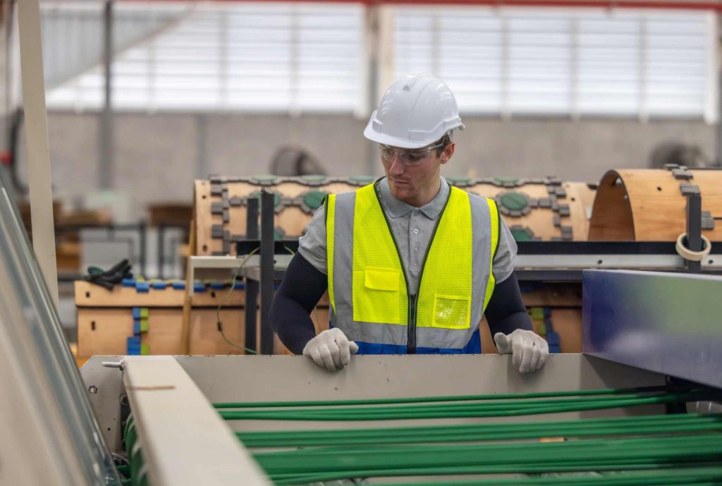 Man inspecting machinery in a factory | Featured image for the How is Plasterboard Made blog from BetaBoard.